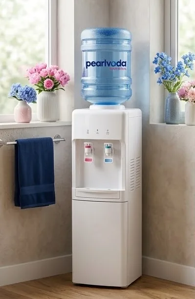 White floor-standing 19L water dispenser with a full blue bottle on top, placed in a bright, clean home corner beside a window